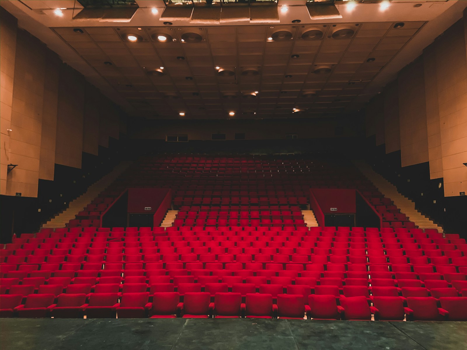 Rows of empty red upholstered seats in a theater, seen from the side